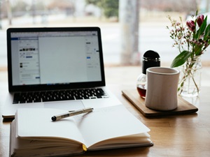 journal and coffee mug next to an open laptop